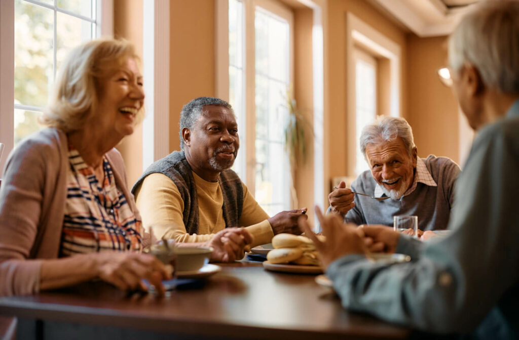 A group of seniors sitting around a table, eating and enjoying afternoon tea while smiling and chatting with each other