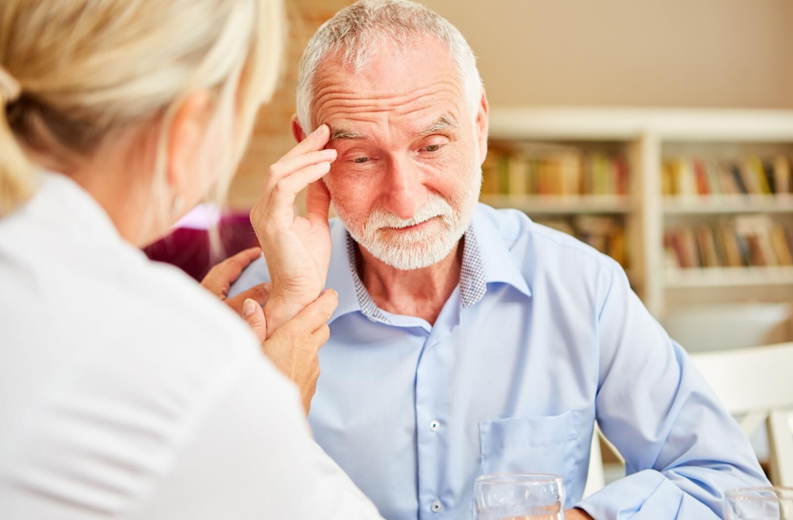 a man sits in a chair holding his head in concern