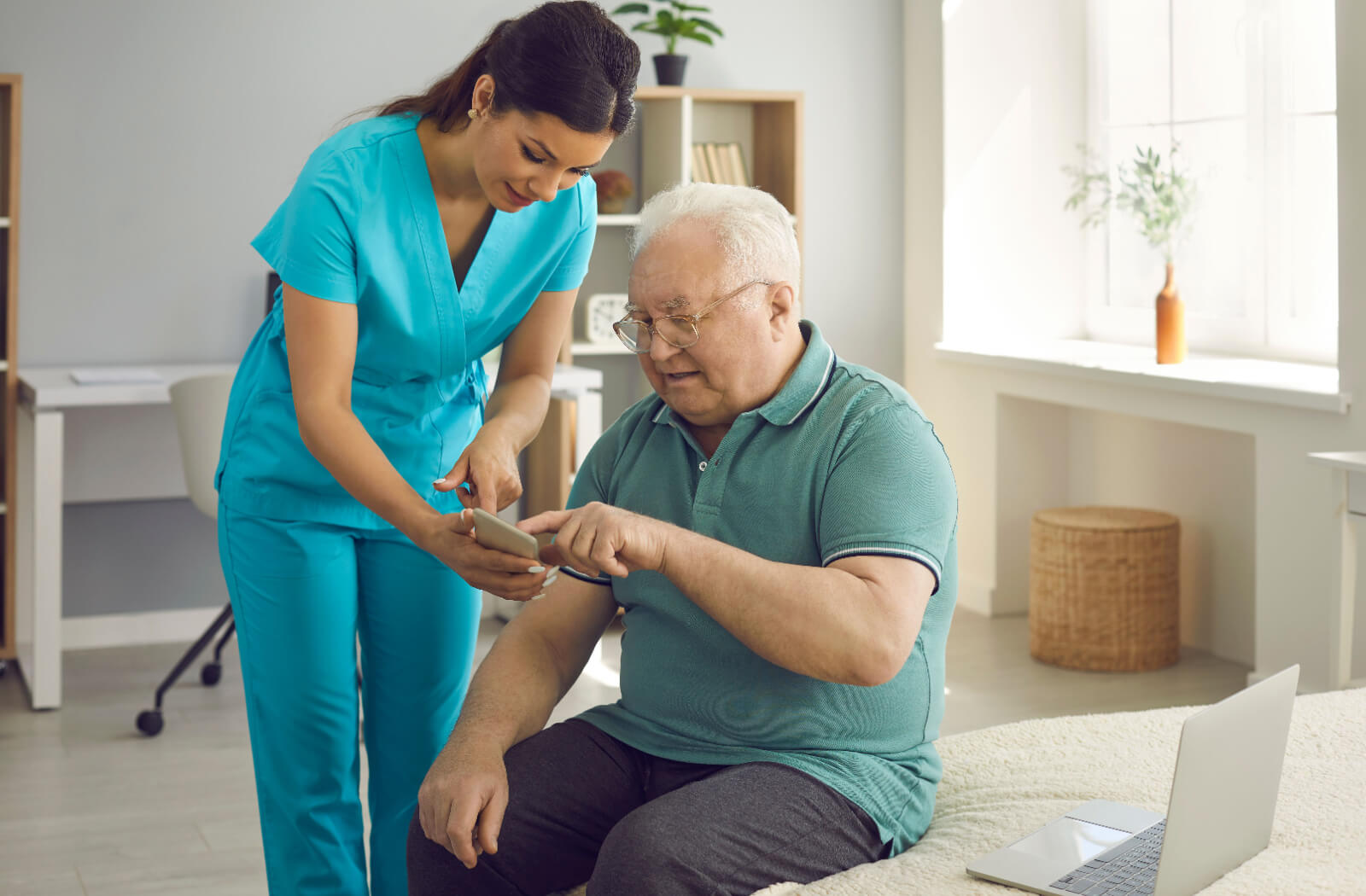 A caregiver explaining to a resident in senior living how AI-enabled fall detection helps keep them safe and showing them their phone.