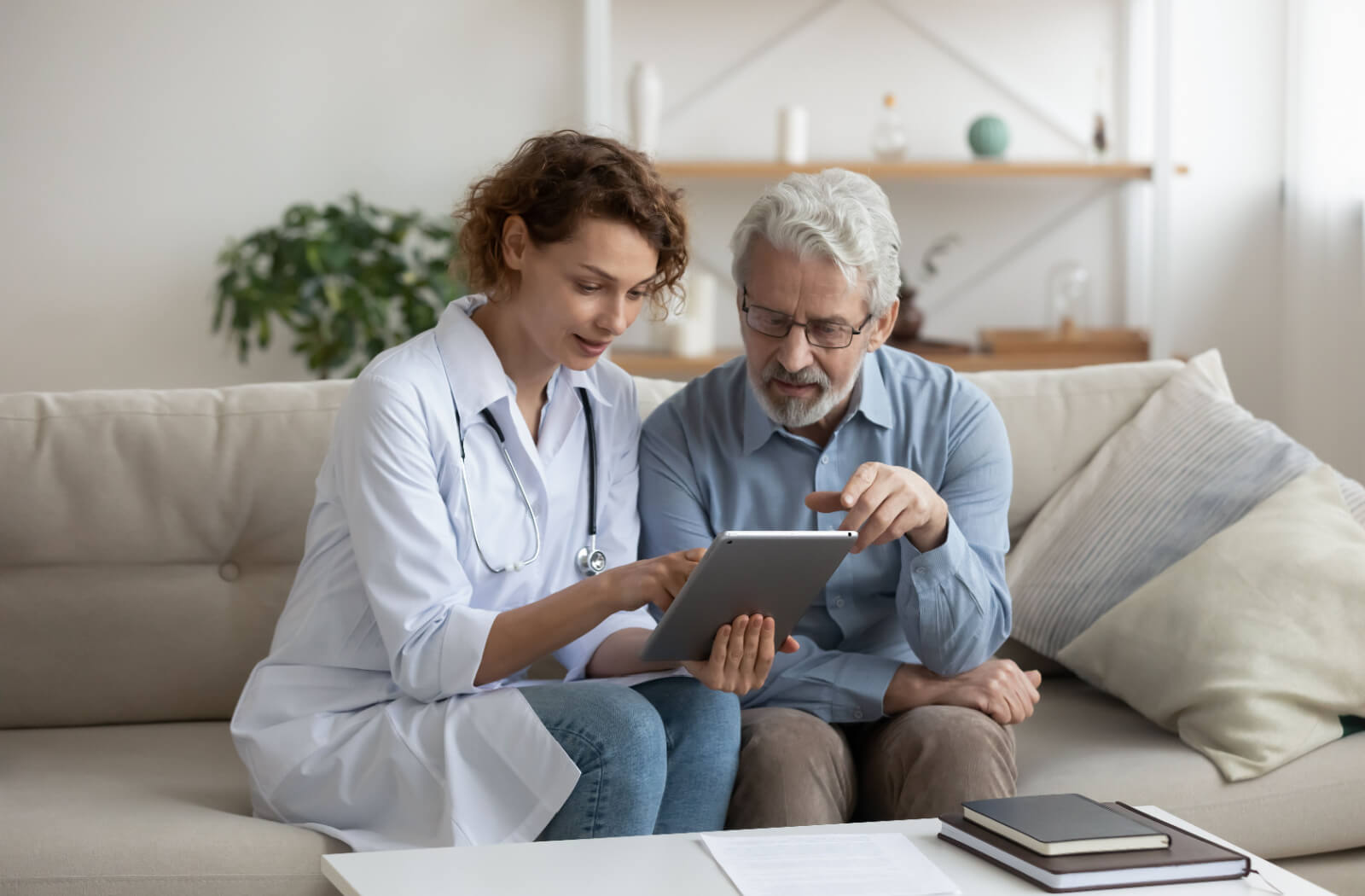 A caregiver and an older adult sitting together looking at a tablet to determine the cause of dementia-like symptoms.