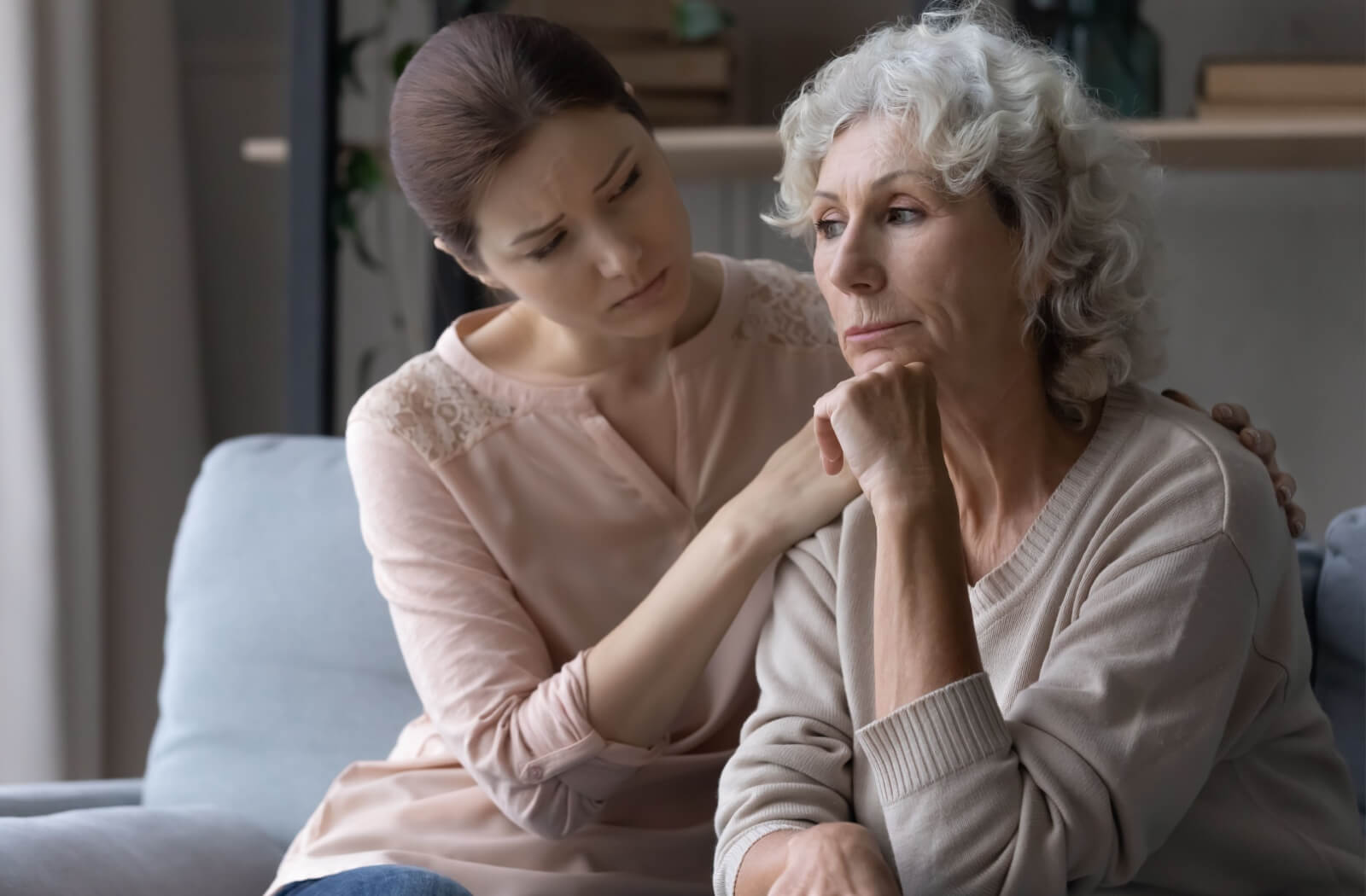 A concerned adult child sitting with their parent who has dementia and comforting them.