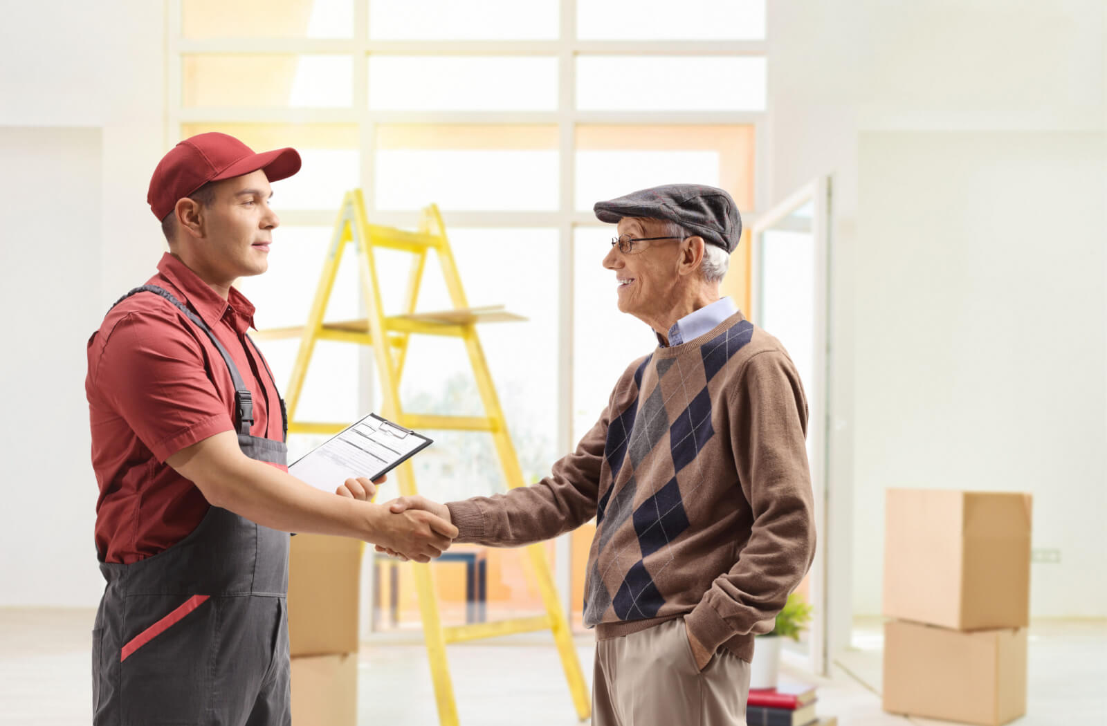 A senior man shaking hands with a moving company staff.