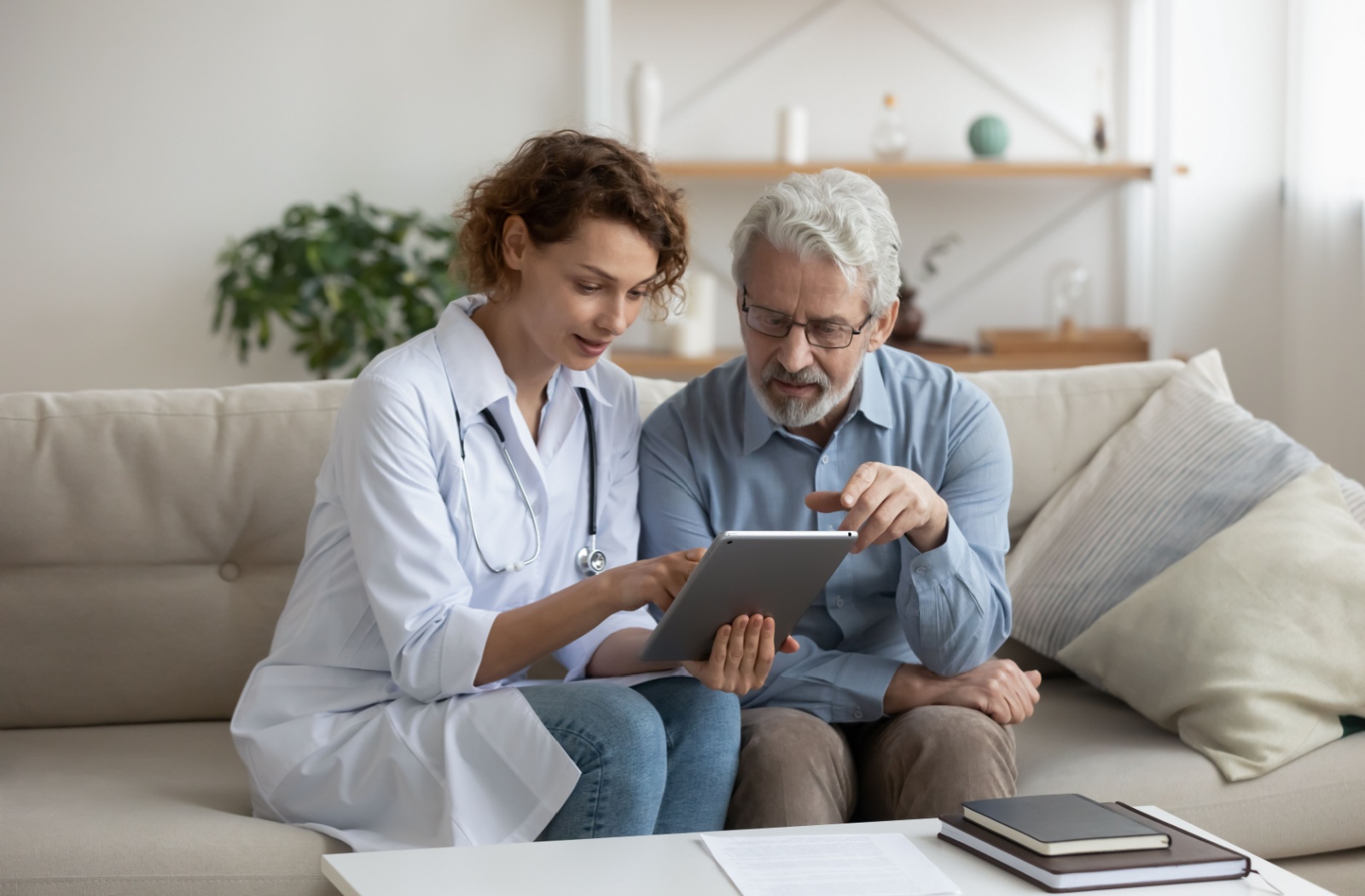 A caregiver showing an older adult a tablet with fall-detection technology in a senior living community.