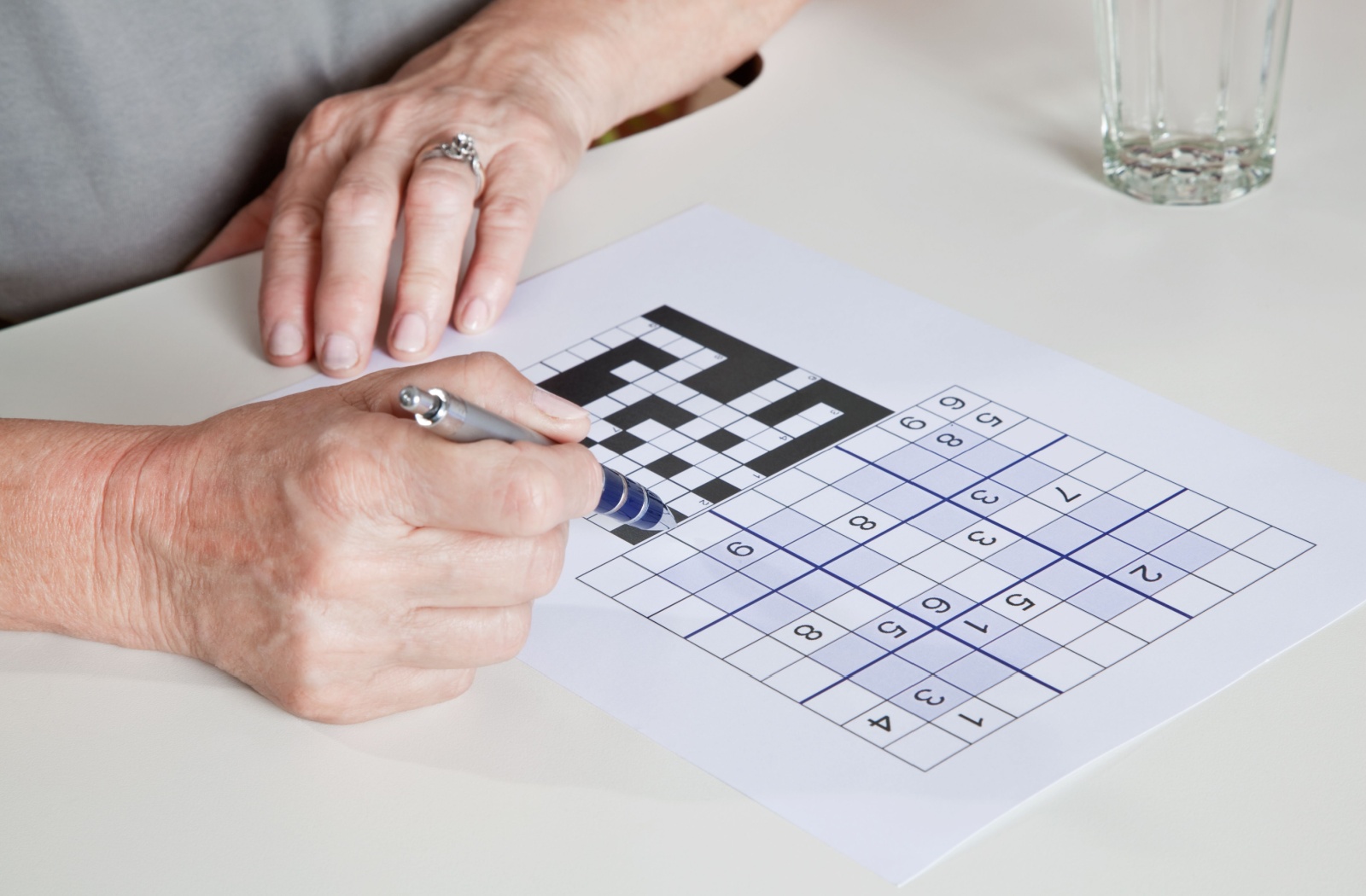 A close-up image of an older adult doing a Sudoku puzzle.