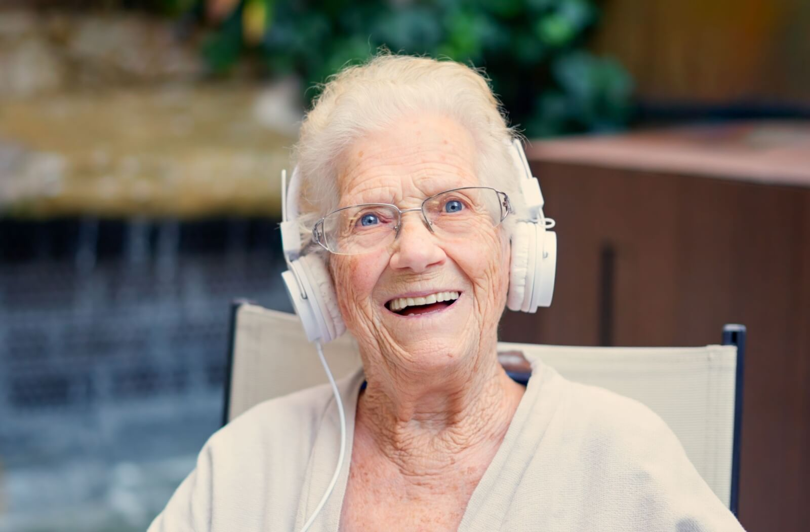 A senior with dementia listens to music through headphones and smiles while reminiscing about it.
